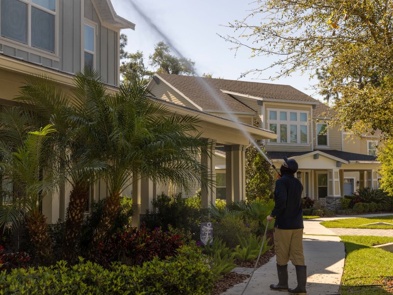 a pressure washing machine spraying water onto the exterior wall of a house during a cleaning process