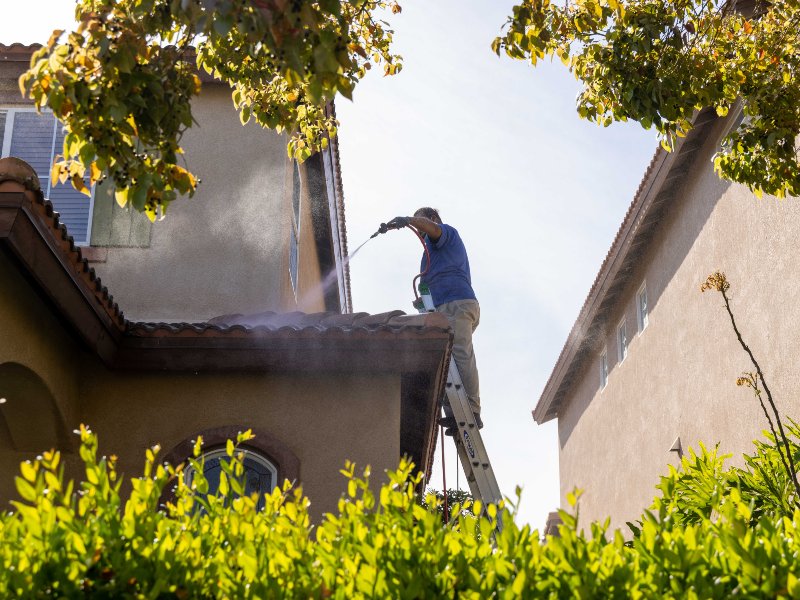 worker washing the roof with pressurized water