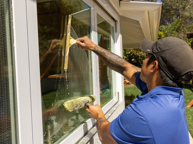 A professional window cleaner using a squeegee to clean the exterior windows